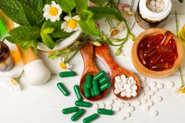 Ahşap zemin üzerinde alternatif ilaç bitkisel kapsül organik ilaç. Bitki ve tablet çeşitleri, vitaminler ve diyet takviyeleri. Sağlıklı yaşam için tıbbi ve şifalı bitkiler.