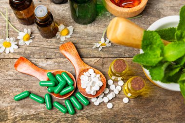 Ahşap zemin üzerinde alternatif ilaç bitkisel kapsül organik ilaç. Bitki ve tablet çeşitleri, vitaminler ve diyet takviyeleri. Sağlıklı yaşam için tıbbi ve şifalı bitkiler.