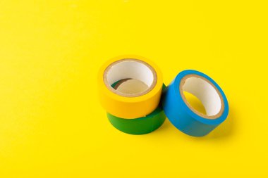 Parlak renkli arka plandaki bant yalıtılıyor. Farklı renkte izolasyon bantları. Yalıtım bandı. İnşaat aletleri. Elektrikçi aletleri. Bir parça koli bandı. Metin için boşluk. Boşluğu kopyala.