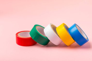 Parlak renkli arka plandaki bant yalıtılıyor. Farklı renkte izolasyon bantları. Yalıtım bandı. İnşaat aletleri. Elektrikçi aletleri. Bir parça koli bandı. Metin için boşluk. Boşluğu kopyala.