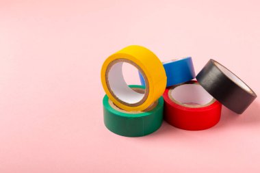 Parlak renkli arka plandaki bant yalıtılıyor. Farklı renkte izolasyon bantları. Yalıtım bandı. İnşaat aletleri. Elektrikçi aletleri. Bir parça koli bandı. Metin için boşluk. Boşluğu kopyala.