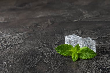 Arka planda nane ve buz var. Yeşil taze nane ve buz küpü. Nane yaprağı, buz küpü ve soğuk içecek için su damlası. Üst Manzara. Mesaj için yer var. Boşluğu kopyala.