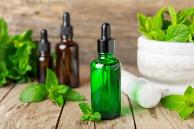 Ahşap bir arka planda esaslı bir nane şekeri. Naneli esaslı yağ ve taze nane yaprakları. Bir şişe aromaterapi yağı. Nane özütü. Doğal kozmetik konsepti, spa bakımı. Boşluğu kopyala