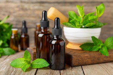 Ahşap bir arka planda esaslı bir nane şekeri. Naneli esaslı yağ ve taze nane yaprakları. Bir şişe aromaterapi yağı. Nane özütü. Doğal kozmetik konsepti, spa bakımı. Boşluğu kopyala