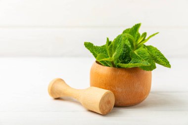 Ahşap zemin üzerinde havan ve kabuk ile taze nane. Melissa gider. Şifalı bitkiler, ilaç için havanda yeşil nane yaprakları. Mesaj için alan. Boşluğu kopyala.