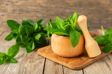 Ahşap zemin üzerinde havan ve kabuk ile taze nane. Melissa gider. Şifalı bitkiler, ilaç için havanda yeşil nane yaprakları. Mesaj için alan. Boşluğu kopyala.