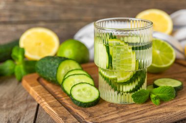 Salatalık suyu, limon, nane ve ahşap bir masada. İçme bardağında dilimlenmiş salatalık ile karıştırılmış su. Tonik ferahlatıcı bir içecek. Salatalık limonata. Doğal soğutma içeceği. Boşluğu kopyala.