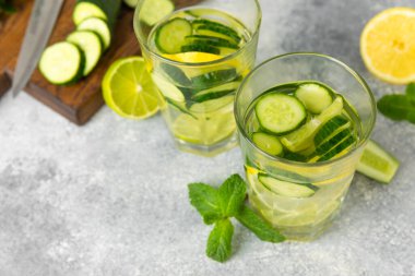 Salatalık suyu, limon, nane ve ahşap bir masada. İçme bardağında dilimlenmiş salatalık ile karıştırılmış su. Tonik ferahlatıcı bir içecek. Salatalık limonata. Doğal soğutma içeceği. Boşluğu kopyala.
