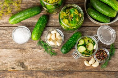 Ahşap bir arka planda kavanozda taze tuzlanmış ev yapımı salatalıklar. Dereotlu, sarımsaklı ve biberli salatalık turşusu. Konserve salatalık, salatalık ve penis. Ev yapımı koruma..