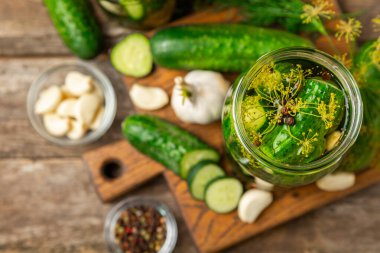 Ahşap bir arka planda kavanozda taze tuzlanmış ev yapımı salatalıklar. Dereotlu, sarımsaklı ve biberli salatalık turşusu. Konserve salatalık, salatalık ve penis. Ev yapımı koruma..