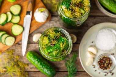 Ahşap bir arka planda kavanozda taze tuzlanmış ev yapımı salatalıklar. Dereotlu, sarımsaklı ve biberli salatalık turşusu. Konserve salatalık, salatalık ve penis. Ev yapımı koruma..