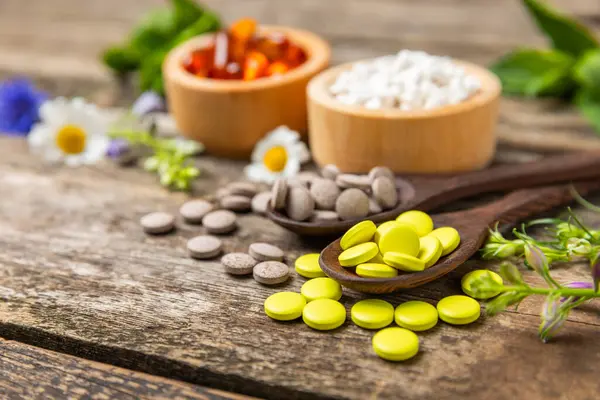 Ahşap zemin üzerinde alternatif ilaç bitkisel kapsül organik ilaç. Bitki ve tablet çeşitleri, vitaminler ve diyet takviyeleri. Sağlıklı yaşam için tıbbi ve şifalı bitkiler.