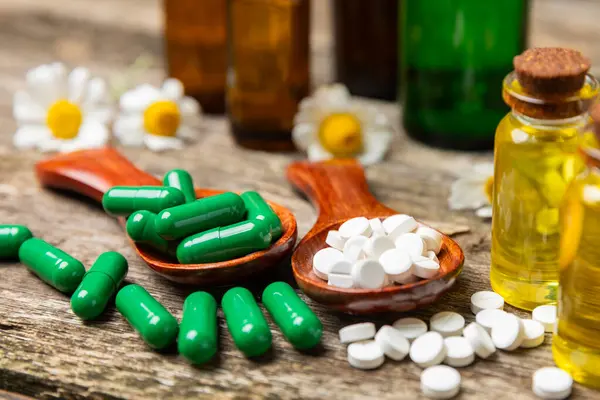 Ahşap zemin üzerinde alternatif ilaç bitkisel kapsül organik ilaç. Bitki ve tablet çeşitleri, vitaminler ve diyet takviyeleri. Sağlıklı yaşam için tıbbi ve şifalı bitkiler.
