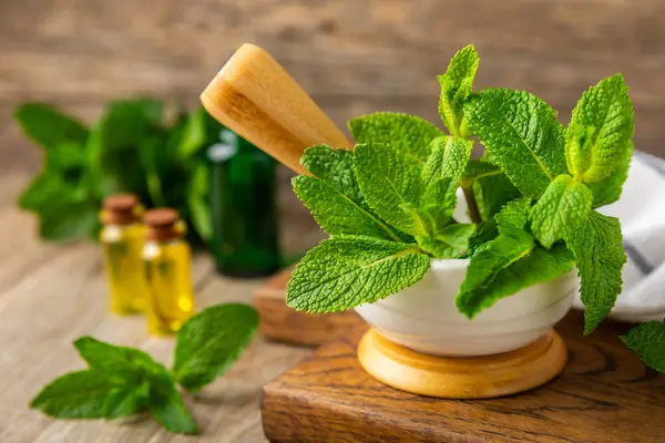 Ahşap zemin üzerinde havan ve kabuk ile taze nane. Melissa gider. Şifalı bitkiler, ilaç için havanda yeşil nane yaprakları. Mesaj için alan. Boşluğu kopyala.