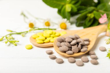 Ahşap zemin üzerinde alternatif ilaç bitkisel kapsül organik ilaç. Bitki ve tablet çeşitleri, vitaminler ve diyet takviyeleri. Sağlıklı yaşam için tıbbi ve şifalı bitkiler.