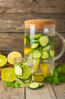 Salatalık suyu, limon, nane ve ahşap bir masada. İçme bardağında dilimlenmiş salatalık ile karıştırılmış su. Tonik ferahlatıcı bir içecek. Salatalık limonata. Doğal soğutma içeceği. Boşluğu kopyala.