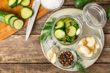 Ahşap bir arka planda kavanozda taze tuzlanmış ev yapımı salatalıklar. Dereotlu, sarımsaklı ve biberli salatalık turşusu. Konserve salatalık, salatalık ve penis. Ev yapımı koruma..