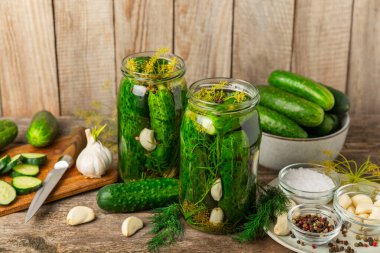 Ahşap bir arka planda kavanozda taze tuzlanmış ev yapımı salatalıklar. Dereotlu, sarımsaklı ve biberli salatalık turşusu. Konserve salatalık, salatalık ve penis. Ev yapımı koruma..