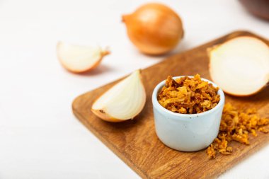 Tahta bir masada kasede kızarmış soğan. Kızarmış soğan. Bulaşık çeşnisi. Baharatlar. Salata sosu. Mesaj için yer var. Boşluğu kopyala