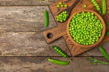 Ahşap zemin üzerinde yeşil bezelyeler olan taze bezelye kabukları. Tatlı yeşil bezelyeler. Yeşil bezelye fasulyesi sebzesi. Vejetaryen. Sağlıklı sebze. Boşluğu kopyala