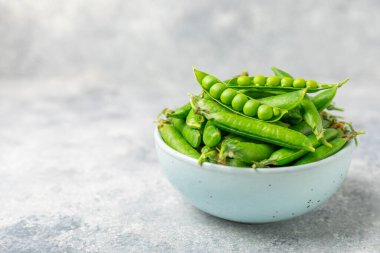 Ahşap zemin üzerinde yeşil bezelyeler olan taze bezelye kabukları. Tatlı yeşil bezelyeler. Yeşil bezelye fasulyesi sebzesi. Vejetaryen. Sağlıklı sebze. Boşluğu kopyala
