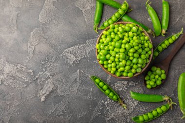 Ahşap zemin üzerinde yeşil bezelyeler olan taze bezelye kabukları. Tatlı yeşil bezelyeler. Yeşil bezelye fasulyesi sebzesi. Vejetaryen. Sağlıklı sebze. Boşluğu kopyala