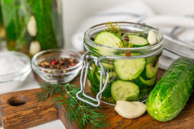 Ahşap bir arka planda kavanozda taze tuzlanmış ev yapımı salatalıklar. Dereotlu, sarımsaklı ve biberli salatalık turşusu. Konserve salatalık, salatalık ve penis. Ev yapımı koruma..