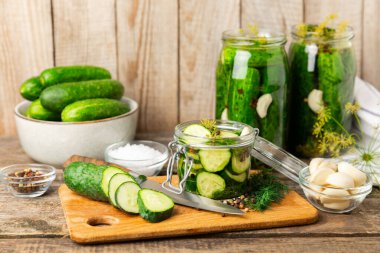 Ahşap bir arka planda kavanozda taze tuzlanmış ev yapımı salatalıklar. Dereotlu, sarımsaklı ve biberli salatalık turşusu. Konserve salatalık, salatalık ve penis. Ev yapımı koruma..