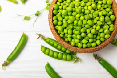 Ahşap zemin üzerinde yeşil bezelyeler olan taze bezelye kabukları. Tatlı yeşil bezelyeler. Yeşil bezelye fasulyesi sebzesi. Vejetaryen. Sağlıklı sebze. Boşluğu kopyala