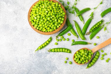 Ahşap zemin üzerinde yeşil bezelyeler olan taze bezelye kabukları. Tatlı yeşil bezelyeler. Yeşil bezelye fasulyesi sebzesi. Vejetaryen. Sağlıklı sebze. Boşluğu kopyala