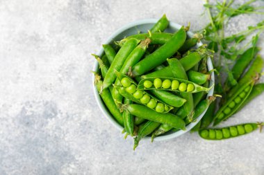Ahşap zemin üzerinde yeşil bezelyeler olan taze bezelye kabukları. Tatlı yeşil bezelyeler. Yeşil bezelye fasulyesi sebzesi. Vejetaryen. Sağlıklı sebze. Boşluğu kopyala
