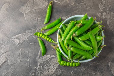 Ahşap zemin üzerinde yeşil bezelyeler olan taze bezelye kabukları. Tatlı yeşil bezelyeler. Yeşil bezelye fasulyesi sebzesi. Vejetaryen. Sağlıklı sebze. Boşluğu kopyala