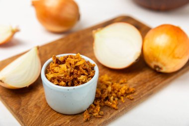 Tahta bir masada kasede kızarmış soğan. Kızarmış soğan. Bulaşık çeşnisi. Baharatlar. Salata sosu. Mesaj için yer var. Boşluğu kopyala