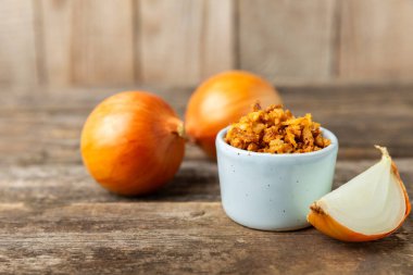 Tahta bir masada kasede kızarmış soğan. Kızarmış soğan. Bulaşık çeşnisi. Baharatlar. Salata sosu. Mesaj için yer var. Boşluğu kopyala