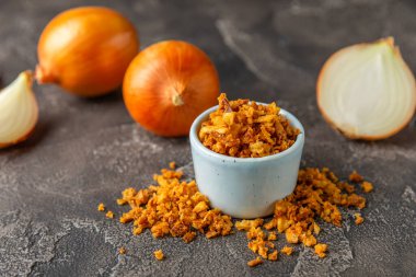 Tahta bir masada kasede kızarmış soğan. Kızarmış soğan. Bulaşık çeşnisi. Baharatlar. Salata sosu. Mesaj için yer var. Boşluğu kopyala