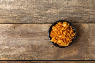 Tahta bir masada kasede kızarmış soğan. Kızarmış soğan. Bulaşık çeşnisi. Baharatlar. Salata sosu. Mesaj için yer var. Boşluğu kopyala