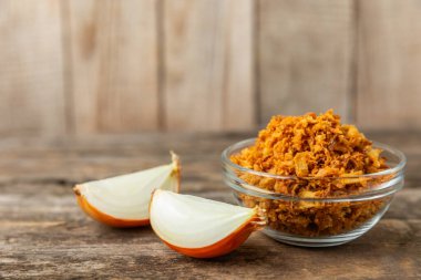 Tahta bir masada kasede kızarmış soğan. Kızarmış soğan. Bulaşık çeşnisi. Baharatlar. Salata sosu. Mesaj için yer var. Boşluğu kopyala