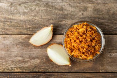 Tahta bir masada kasede kızarmış soğan. Kızarmış soğan. Bulaşık çeşnisi. Baharatlar. Salata sosu. Mesaj için yer var. Boşluğu kopyala