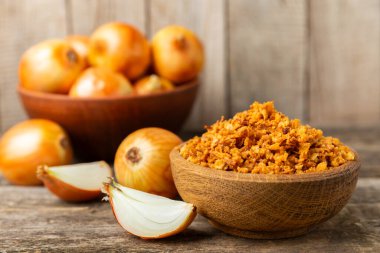 Tahta bir masada kasede kızarmış soğan. Kızarmış soğan. Bulaşık çeşnisi. Baharatlar. Salata sosu. Mesaj için yer var. Boşluğu kopyala