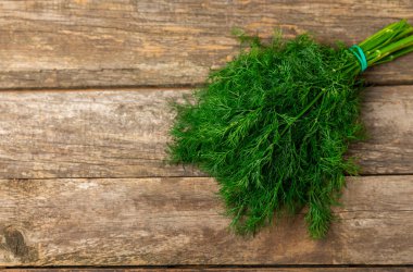 Ahşap arka planda Dill. Taze organik sebzeler. Dill çiftliği. Dereotu yapraklarını kes. Bahar genç deresi sürüsü. Vitaminler. İplik. Aromatik mutfak baharatı. Mesaj için yer. Boşluğu kopyala
