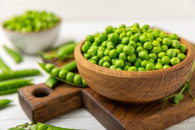Ahşap zemin üzerinde yeşil bezelyeler olan taze bezelye kabukları. Tatlı yeşil bezelyeler. Yeşil bezelye fasulyesi sebzesi. Vejetaryen. Sağlıklı sebze. Boşluğu kopyala