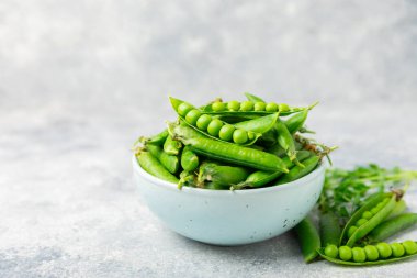 Ahşap zemin üzerinde yeşil bezelyeler olan taze bezelye kabukları. Tatlı yeşil bezelyeler. Yeşil bezelye fasulyesi sebzesi. Vejetaryen. Sağlıklı sebze. Boşluğu kopyala