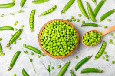 Ahşap zemin üzerinde yeşil bezelyeler olan taze bezelye kabukları. Tatlı yeşil bezelyeler. Yeşil bezelye fasulyesi sebzesi. Vejetaryen. Sağlıklı sebze. Boşluğu kopyala
