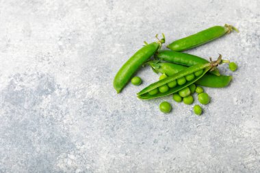 Ahşap zemin üzerinde yeşil bezelyeler olan taze bezelye kabukları. Tatlı yeşil bezelyeler. Yeşil bezelye fasulyesi sebzesi. Vejetaryen. Sağlıklı sebze. Boşluğu kopyala
