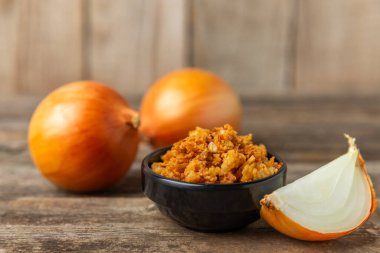 Tahta bir masada kasede kızarmış soğan. Kızarmış soğan. Bulaşık çeşnisi. Baharatlar. Salata sosu. Mesaj için yer var. Boşluğu kopyala