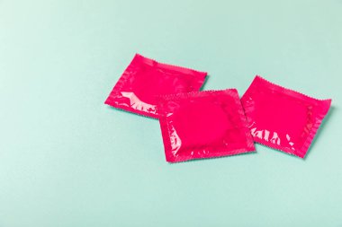 Renkli arka planda prezervatifler. Paketlemede renkli meyve temalı prezervatifler. Güvenli seks konsepti. Doğum kontrol hapı. Farklı doğum kontrol yöntemleri. AİDS önleme. Dünya AIDS Günü. Cinsel sağlık.