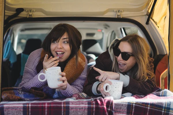 Couple lying inside the van with a cup of coffee - couple with surprised expression - Winter vacation and relationship concept. of surprise - winter vacations and relationship concept.