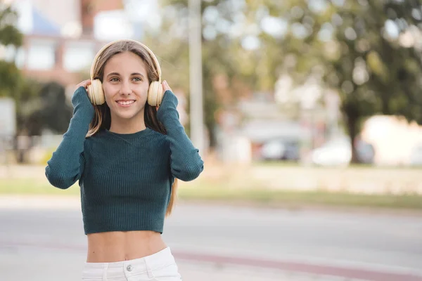 Lisenin Önünde Kablosuz Kulaklıkla Müzik Dinleyen Gülümseyen Genç Öğrenci — Stok fotoğraf