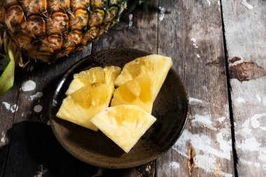 Ahşap arka planda dilimlenmiş ananas, üst manzara, sağlıklı meyve yemeği konsepti.
