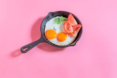 Tavada kızarmış yumurta, pembe arka planda izole edilmiş. Yakın plan, üst manzara, kahvaltı yemeği konsepti..